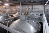 Interior de la cervecería, grandes tanques de almacenamiento de acero para la elaboración de cerveza. - foto de stock