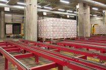 Warehouse,and distribution centre for goods. Steel platforms and pallets, lifting equipment and racking. Shrink wrapped cartons — Stock Photo
