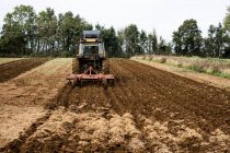 Vue arrière d'un tracteur labourant un champ sur une ferme. — Photo de stock