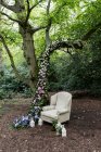 Armchair and flower garland decorations for a woodland naming ceremony. — Stock Photo