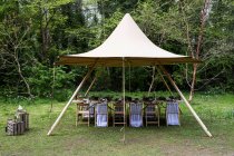 Dining table and chairs under a canopy for a woodland naming ceremony. — Stock Photo