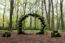 Arco con decorazioni floreali rosa per una cerimonia di denominazione boschiva. — Foto stock