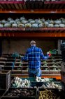 Bauer steht in einer Scheune und sortiert frisch gepflückte Produkte in Gemüsekisten. — Stockfoto