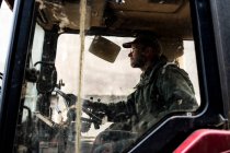 Side view of farmer sitting in the cabin of a tractor. — Stock Photo