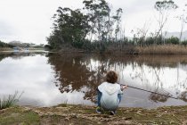 Kleiner Junge sitzt auf einem Flussufer — Stockfoto