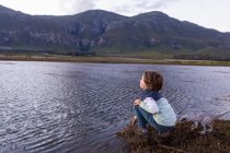 Um menino explorando a costa de uma lagoa na sombra da cordilheira Kleinriver — Fotografia de Stock