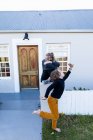 Brother and sister outside their home, boy dancing barefoot on grass. — Stock Photo