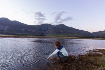Мальчик исследует берег лагуны в тени горного хребта Клейнривер — стоковое фото