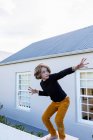 Восьмилетний мальчик балансирует на стене перед домом, позируя перед камерой. — стоковое фото