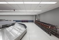 Empty airport luggage claim area, carousels and trolleys. — Stock Photo