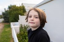 Восьмилетний мальчик с серьезным выражением лица у дома — стоковое фото