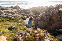 Niño explorando las rocas irregulares y piscinas de roca en la costa del Océano Atlántico, De Kelders, Cabo Occidental, Sudáfrica. - foto de stock