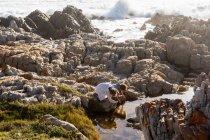 Duas crianças explorando as rochas irregulares e piscinas rochosas na costa do Oceano Atlântico, De Kelders, Western Cape, África do Sul. — Fotografia de Stock