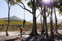 Teenagermädchen und jüngerer Bruder nutzen Seilschaukel auf Wanderweg — Stockfoto