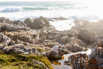 Duas crianças explorando as rochas irregulares e piscinas rochosas na costa do Oceano Atlântico, De Kelders, Western Cape, África do Sul. — Fotografia de Stock