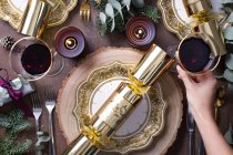 Weihnachten, eine Tischdekoration, Blick über den Kopf, Wein und Kerzen, Teller und Besteck und ein Cracker — Stockfoto