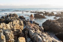 Niño trepando y explorando las rocas y las piscinas, De Kelders, Western Cape, Sudáfrica. - foto de stock