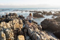 Jovem rapaz escalando e explorando as rochas e piscinas, De Kelders, Western Cape, África do Sul. — Fotografia de Stock
