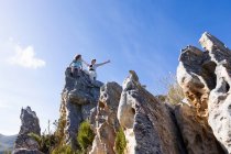 Dos niños escalando sobre grandes formaciones rocosas de arenisca en un sendero natural. - foto de stock