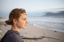 Perfil de uma adolescente olhando para o mar a partir de uma praia ao pôr do sol. — Fotografia de Stock