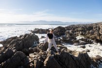 Teenage girl esplorare le rocce frastagliate e piscine rocciose sulla costa dell'Oceano Atlantico, De Kelders, Western Cape, Sud Africa. — Foto stock