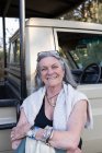 Senior woman smiling standing by a safari vehicle in Botswana. — Stock Photo