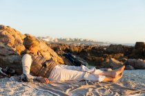 Доросла жінка сидить на піску, відпочиває на пляжі на заході сонця — стокове фото
