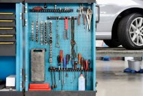 Ferramentas em uma placa azul em um armário de armazenamento organizado em fileiras em uma oficina de reparação de automóveis. — Fotografia de Stock
