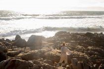 Adolescente explorando las rocas irregulares y las piscinas de rocas en la costa del Océano Atlántico, De Kelders, Cabo Occidental, Sudáfrica. - foto de stock