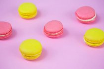 Macaroons rosa e amarelo, biscoitos doces saborosos em uma mesa. — Fotografia de Stock