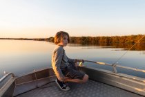 Jeune garçon sur un bateau sur les eaux du delta de l'Okavango au coucher du soleil, Botswana. — Photo de stock