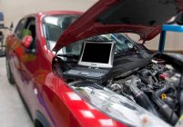Auto in officina e computer con diagnostica sul motore. — Foto stock