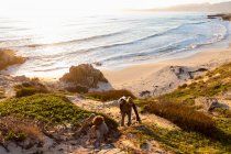 Young boy and mature woman climbing up a cliff path at sunset. — Stock Photo