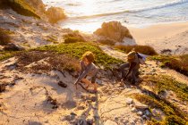Young boy and mature woman climbing up a cliff path at sunset. — Stock Photo