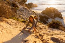 Un ragazzo e una donna che si arrampicano su un ripido pendio sabbioso sopra una spiaggia — Foto stock