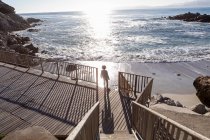 A boy running towards the beach down a set of steps — Stock Photo