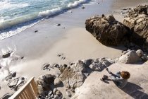 Хлопчик знімає взуття, щоб піти на піщаний пляж — стокове фото