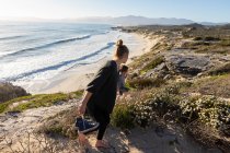 Ein Teenager-Mädchen und ihr Bruder laufen einen Pfad hinunter zu einem Sandstrand — Stockfoto
