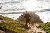 Uma adolescente e seu irmão correndo por um caminho em direção a uma praia de areia — Fotografia de Stock