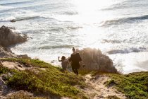 Un'adolescente e suo fratello corrono lungo un sentiero verso una spiaggia sabbiosa — Foto stock