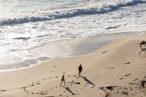 Deux enfants courent et laissent des traces dans le sable doux d'une plage — Photo de stock