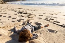 Мальчик сидит на песчаном пляже — стоковое фото