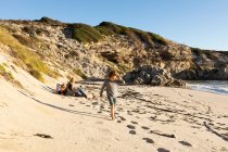 Family on a sandy beach, boy walking through soft sand — Stock Photo