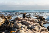 Adolescente caminando a través de rocas dentadas, explorando piscinas de rocas junto al océano - foto de stock