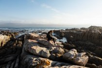 Teenagermädchen geht über zerklüftete Felsen und erkundet Felspfützen am Meer — Stockfoto