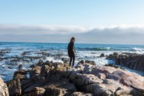 Teenagermädchen geht über zerklüftete Felsen und erkundet Felspfützen am Meer — Stockfoto