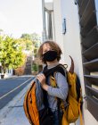 Ein Junge mit einem Rucksack mit schwarzer Gesichtsmaske auf einer Straße. — Stockfoto