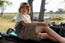 Un jeune garçon dans un véhicule de safari regardant autour du paysage — Photo de stock