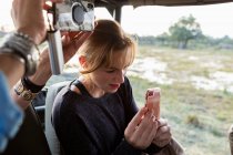 Ragazza adolescente che utilizza lo smart phone per scattare una foto durante una jeep drive safari. — Foto stock