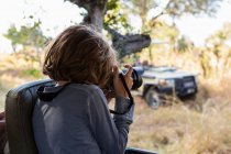 Young boy using a large camera during a jeep drive on safari — Stock Photo